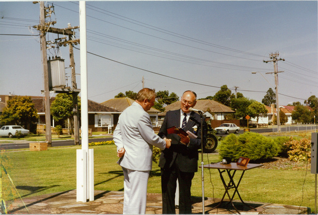 Mayor W.L.J. Crofts presenting award to unidentified person outside the Altona Council Chambers