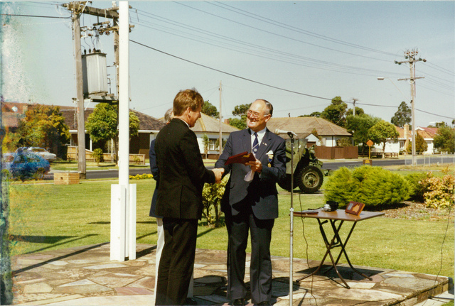 Mayor W.L.J. Crofts presenting an award to an unidentified person at 150th celebrations outside the Altona Council Chambers