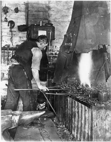 Man working at forge at rear of house, Fitzroy