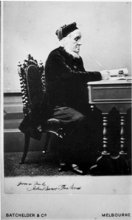 J. P. Fawkner seated at a desk